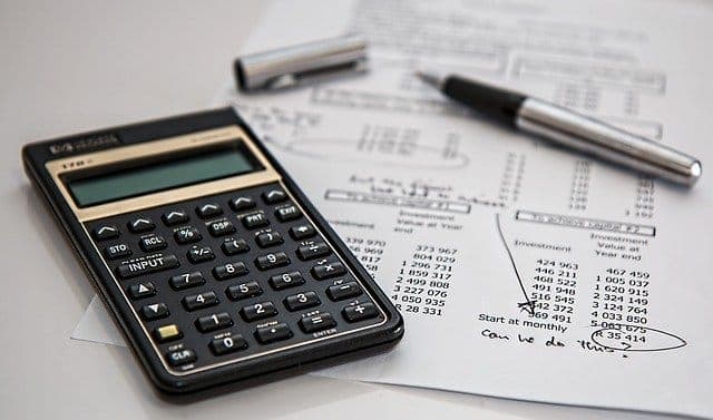 A calculator and a pen resting on a printed financial worksheet